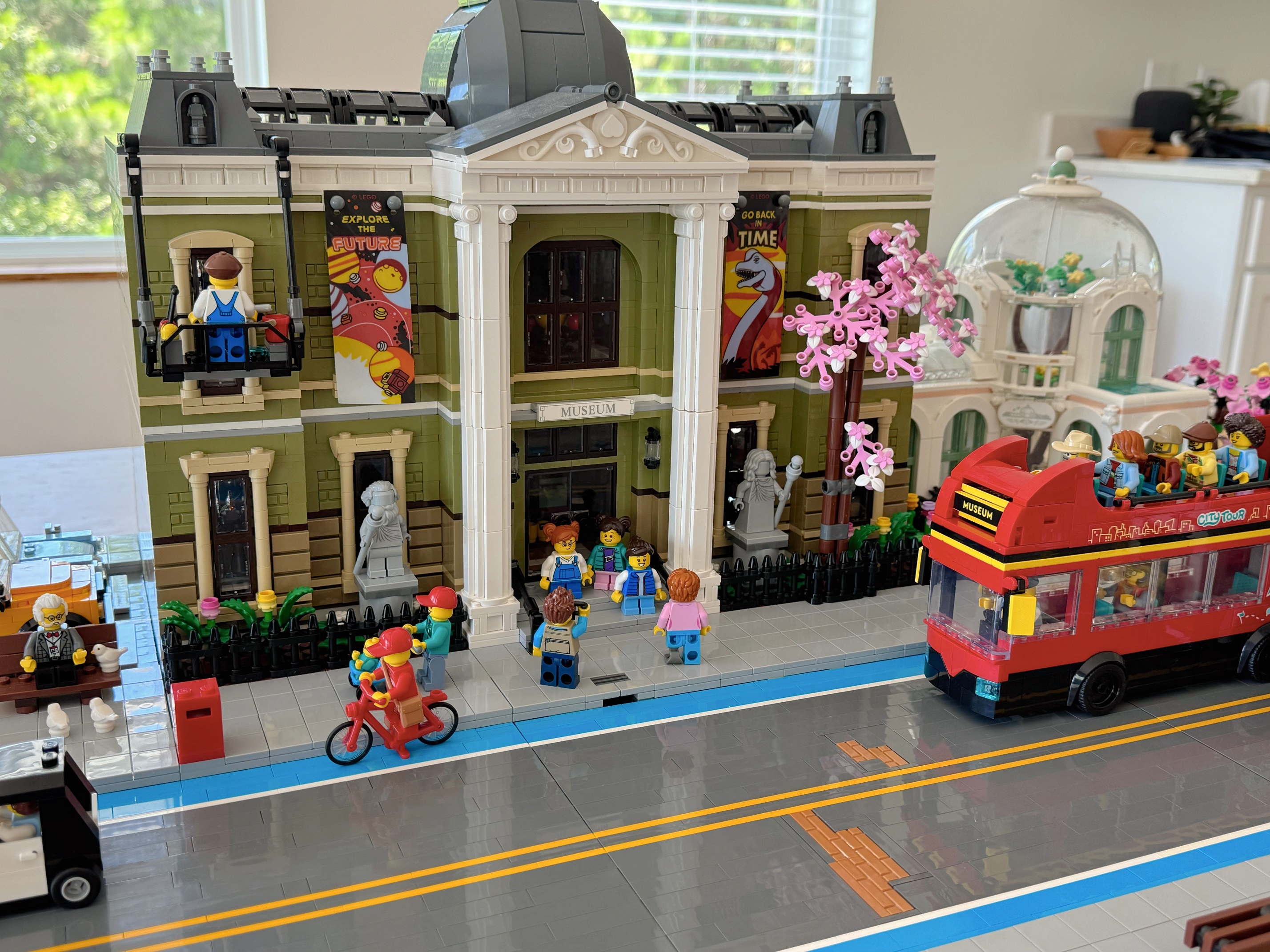 A group of LEGO minifigures in front of the LEGO Natural History Museum with a tour bus in the street